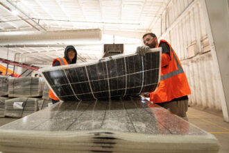 Workers push damaged solar panels into a machine to be recycled at the We Recycle Solar plant in Yuma, Ariz. on Dec. 6, 2023. Credit: Valerie Macon/AFP via Getty Images